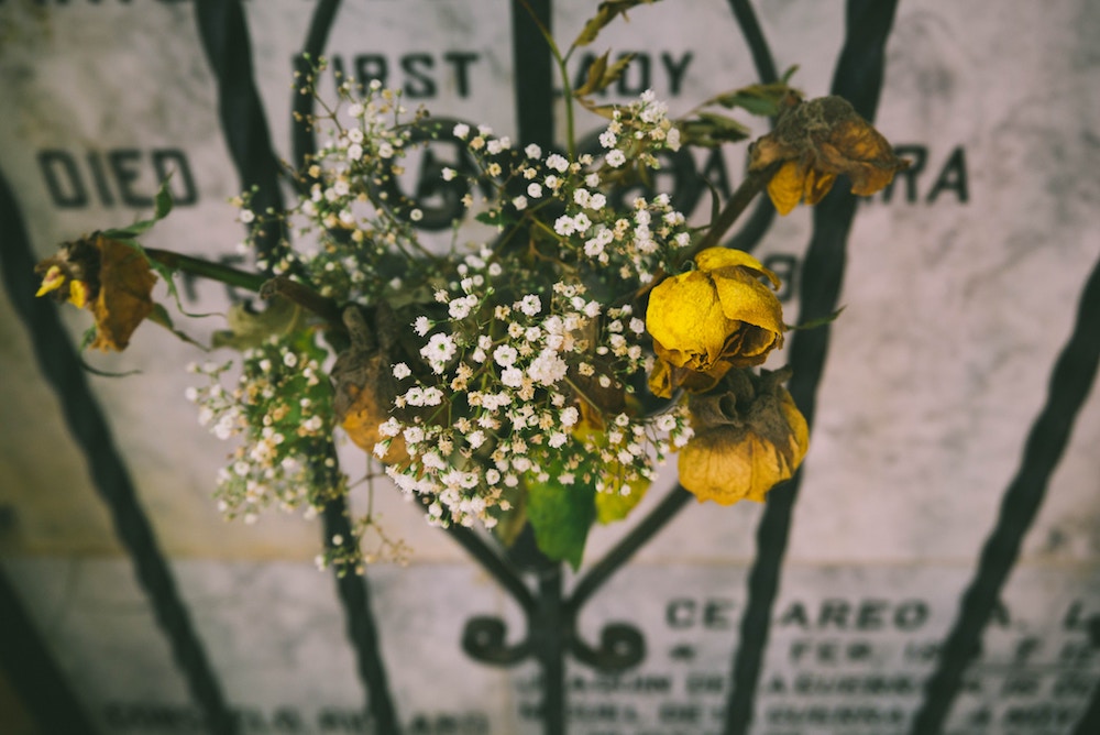 flowers on gate in front of gravestone